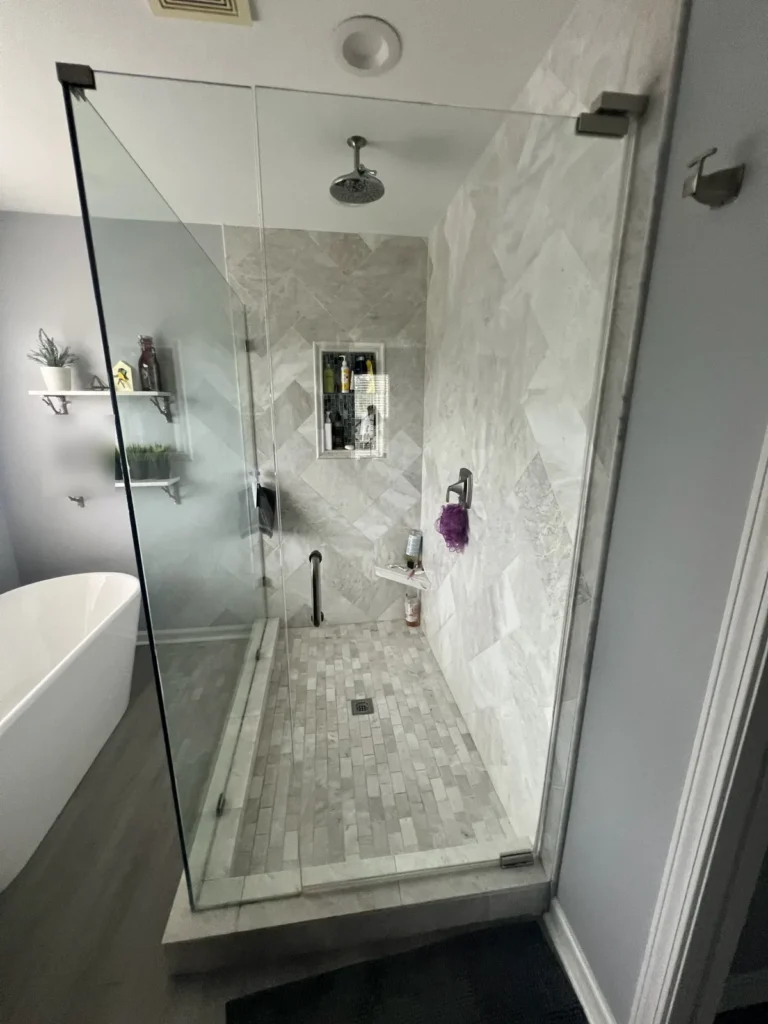 Herringbone marble tile walk-in shower with frameless glass