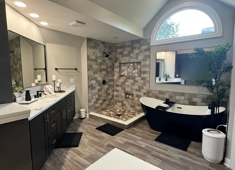 Master bathroom remodel with gray brick-look tile walk-in shower, black freestanding tub and arched window