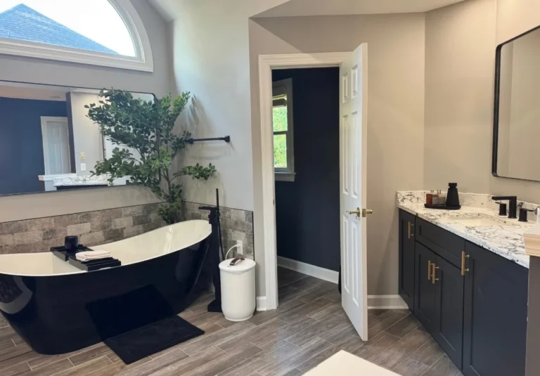 Master bath with black freestanding tub and navy vanity with gold pulls