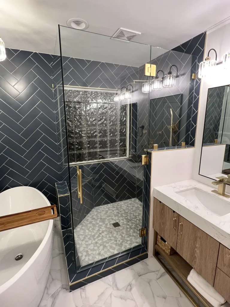 Frameless glass steam shower with navy herringbone tile and gold hardware, Charlotte area