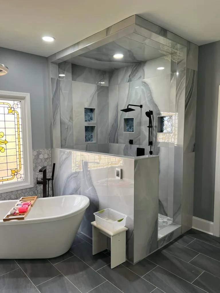 Marble-look tile steam shower and freestanding soaking tub with stained-glass window