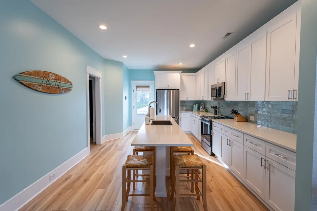 Kitchen remodel with white shaker cabinets, blue-green subway tile backsplash and island seating