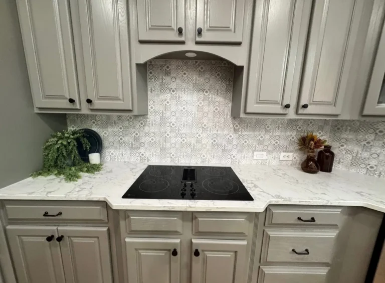 After: gray painted cabinets with patterned tile backsplash over the cooktop